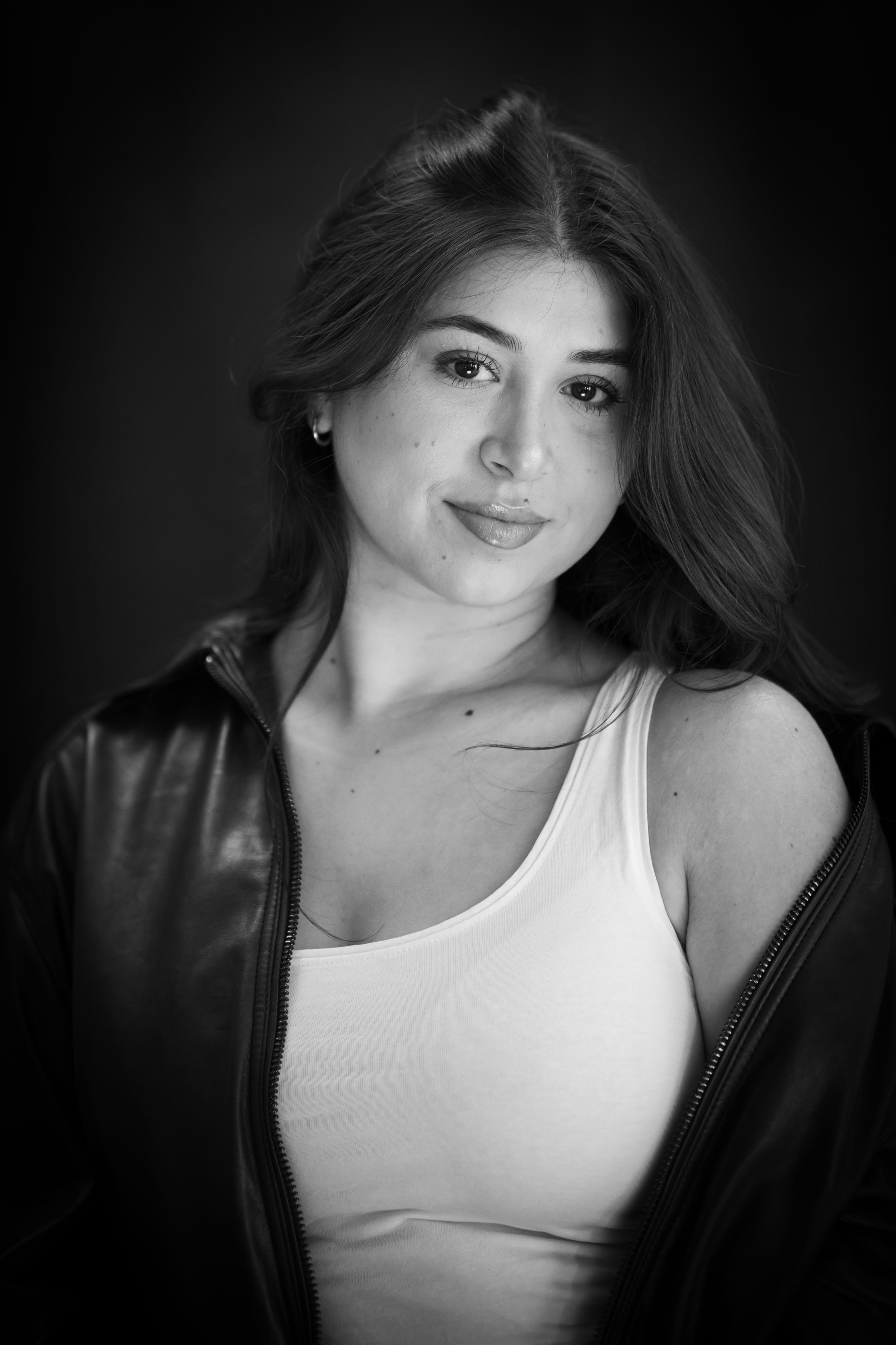 Classic black and white portrait of a young woman wearing a leather jacket in a studio setting.