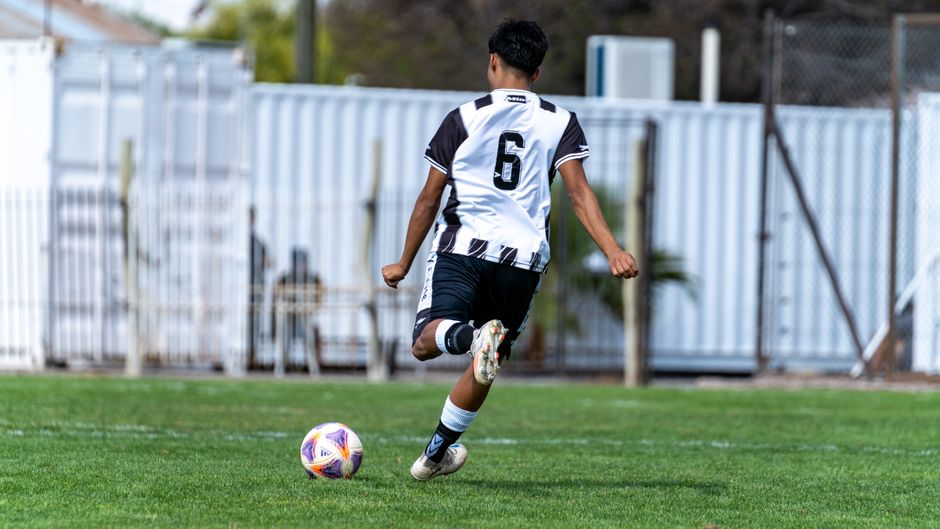 A young soccer player wearing a number 6 jersey kicks the ball during a game.
