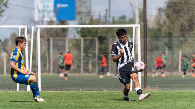 Action shot of two soccer players mid-game on a sunny day, outdoors.