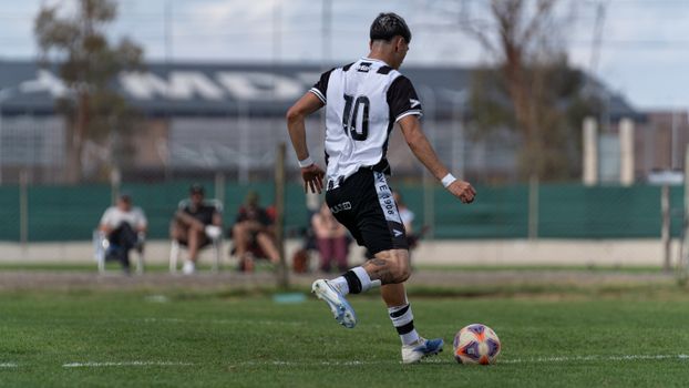 A soccer player wearing a number 10 jersey dribbles the ball during a match.