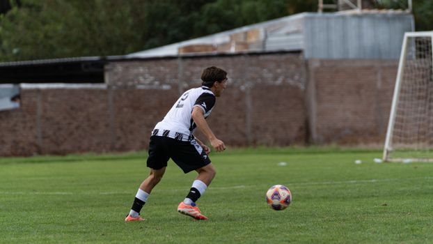 A male soccer player in action on a grassy field during a day match.