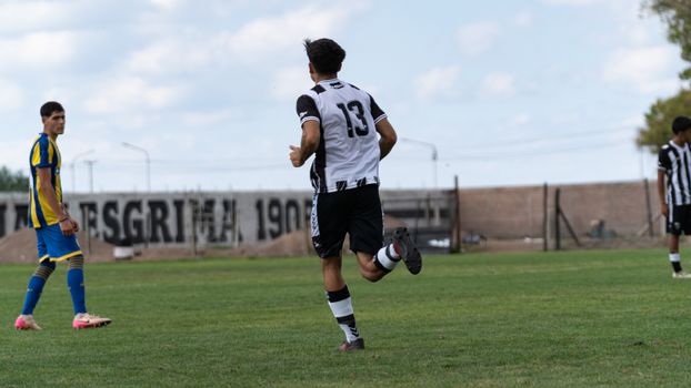 Teen soccer players competing in a match on a grassy field outdoors. Number 13 running.