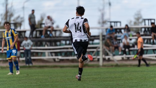 Soccer player in action during an outdoor amateur match with spectators.