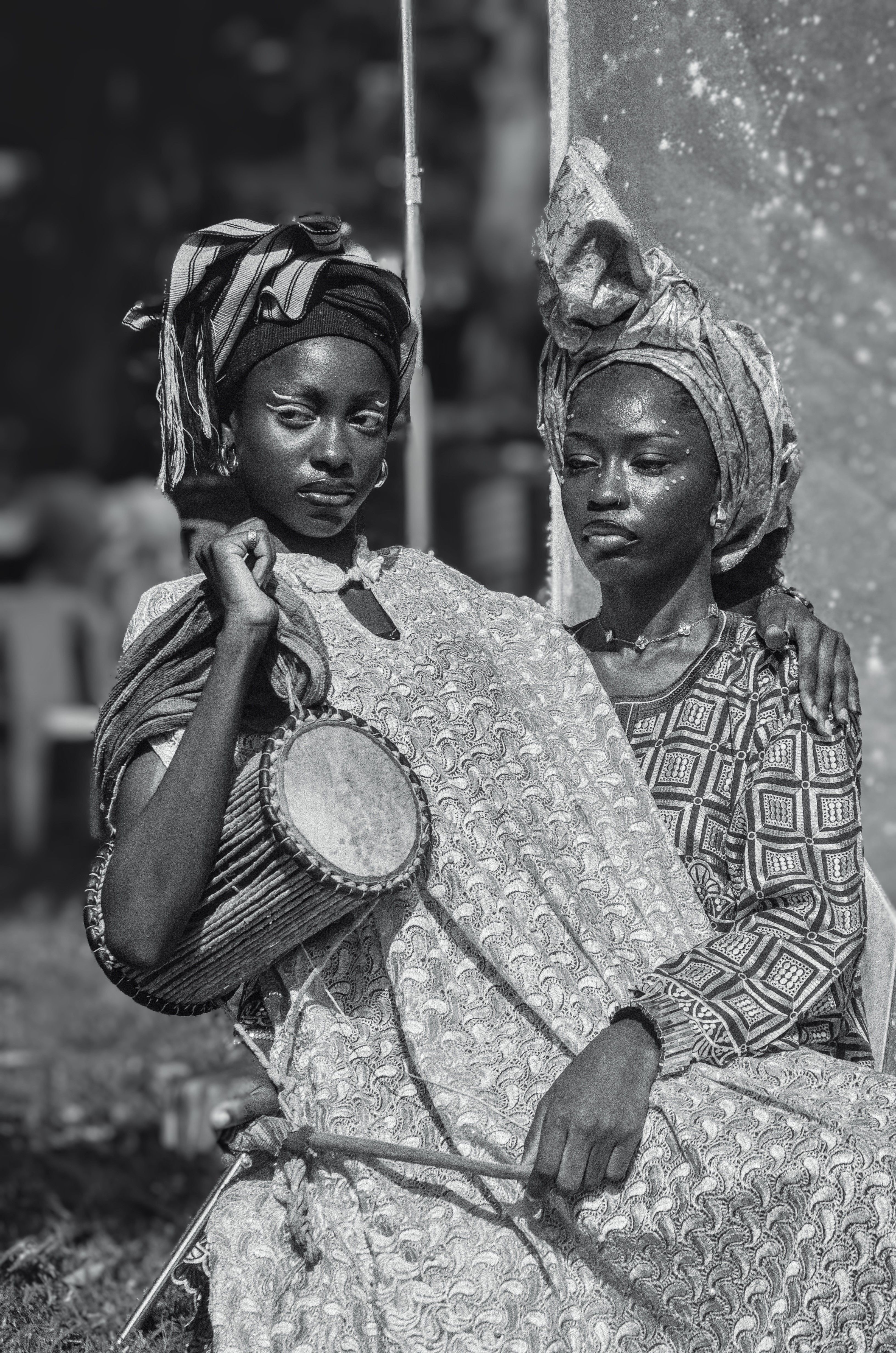 Two Nigerian women in traditional attire holding a drum, depicting cultural heritage in Nigeria.