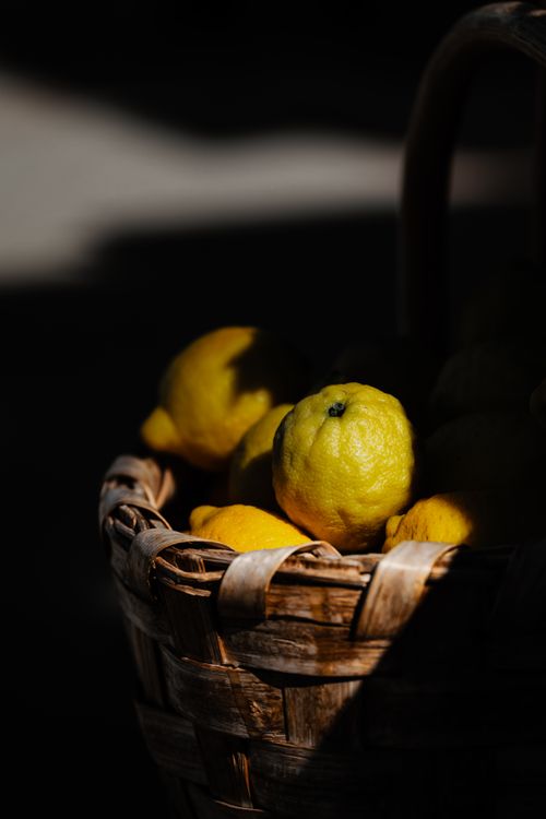 Free Close-up of lemons in a wicker basket with contrasting shadows, highlighting rustic simplicity. Stock Photo