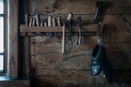 Shoemaker tools hanging on shelf in rustic wooden workshop