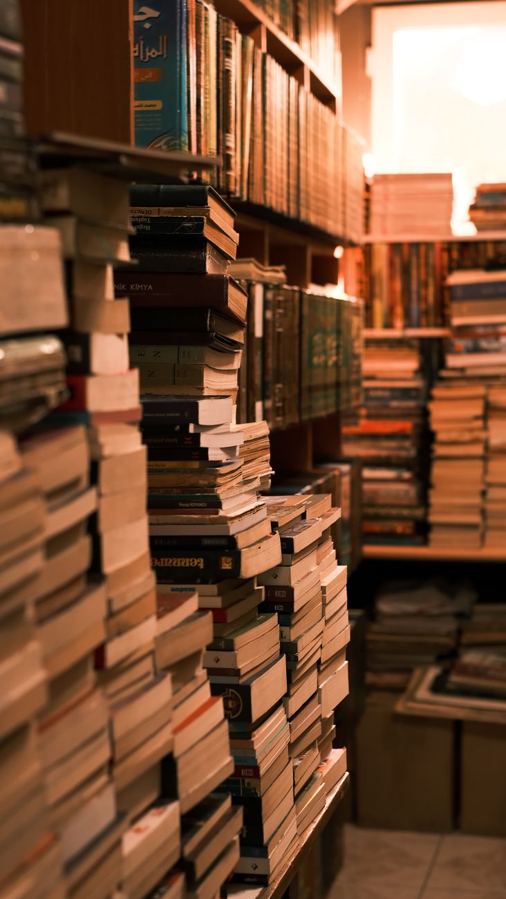 Warmly lit bookshop interior filled with numerous stacks of vintage books. A paradise for book lovers.