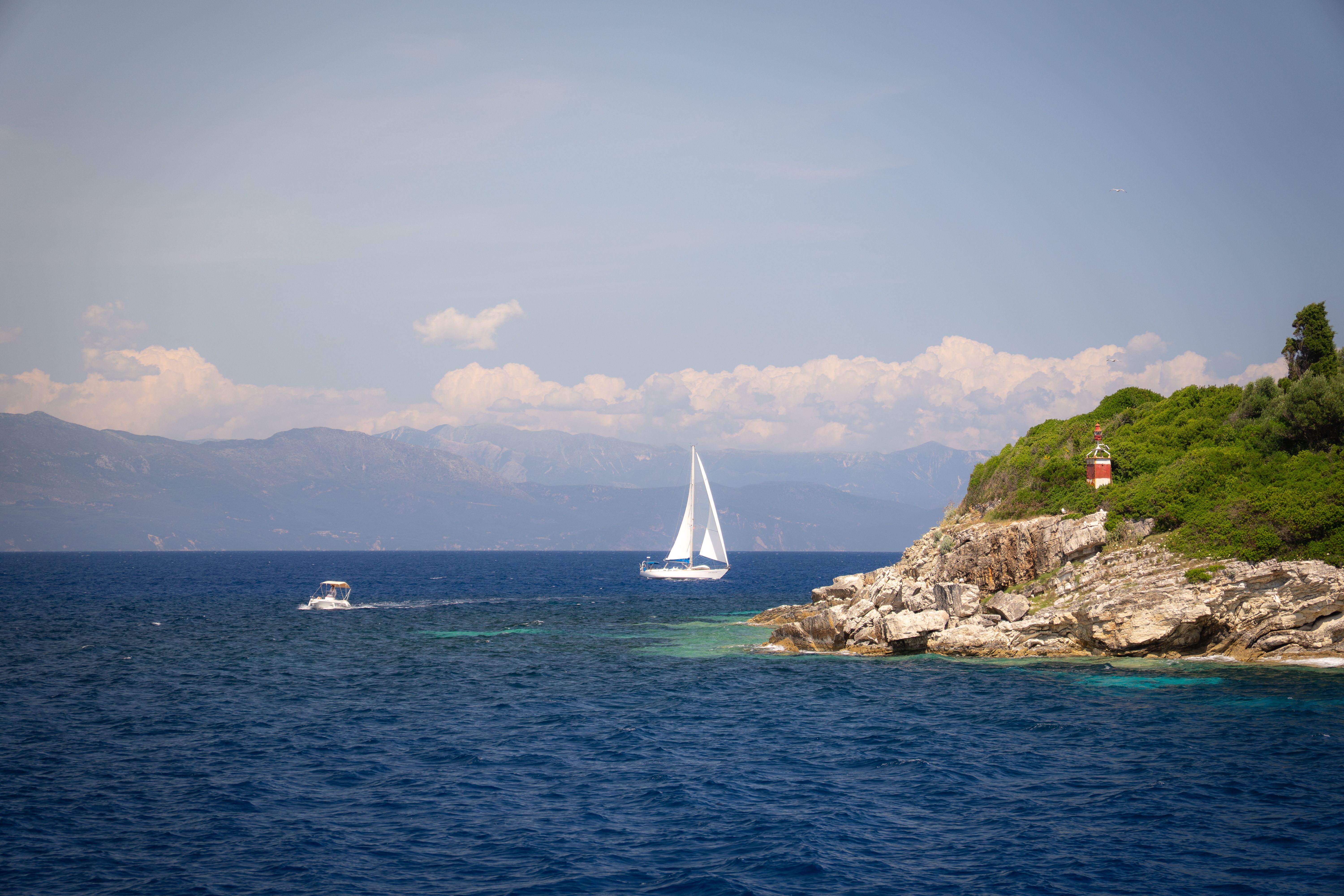 Stunning All-Inclusive Full-Day Cruise & Lunch Review: Sailing Greece's Stunning Sporades Islands Review 2026 - A serene coastal scene with a sailboat near a rocky shore and a small lighthouse.