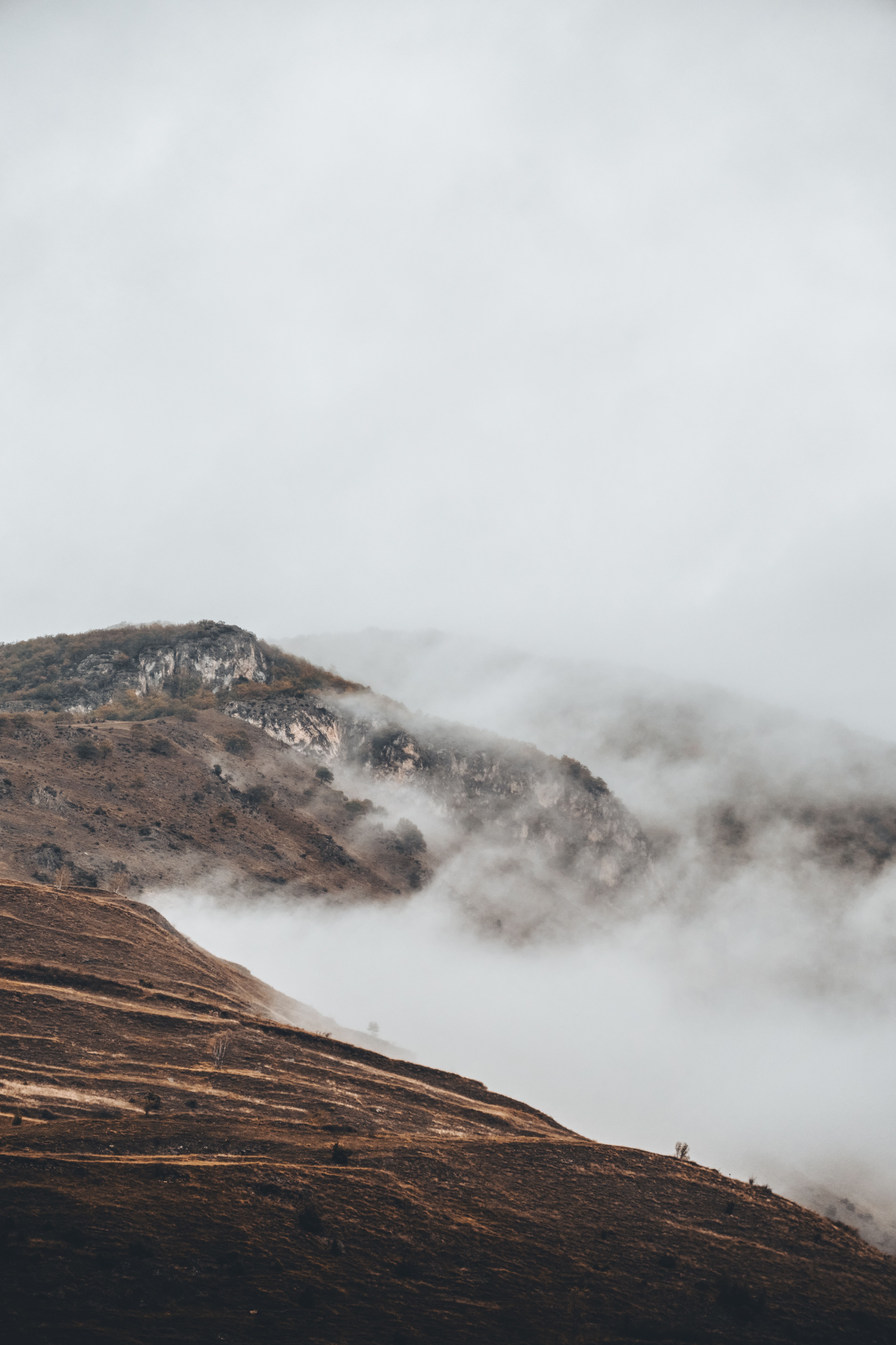 A serene view of the mist-covered mountains in the Pyrenees with a dark and moody atmosphere.