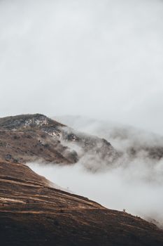 A serene view of the mist-covered mountains in the Pyrenees with a dark and moody atmosphere.