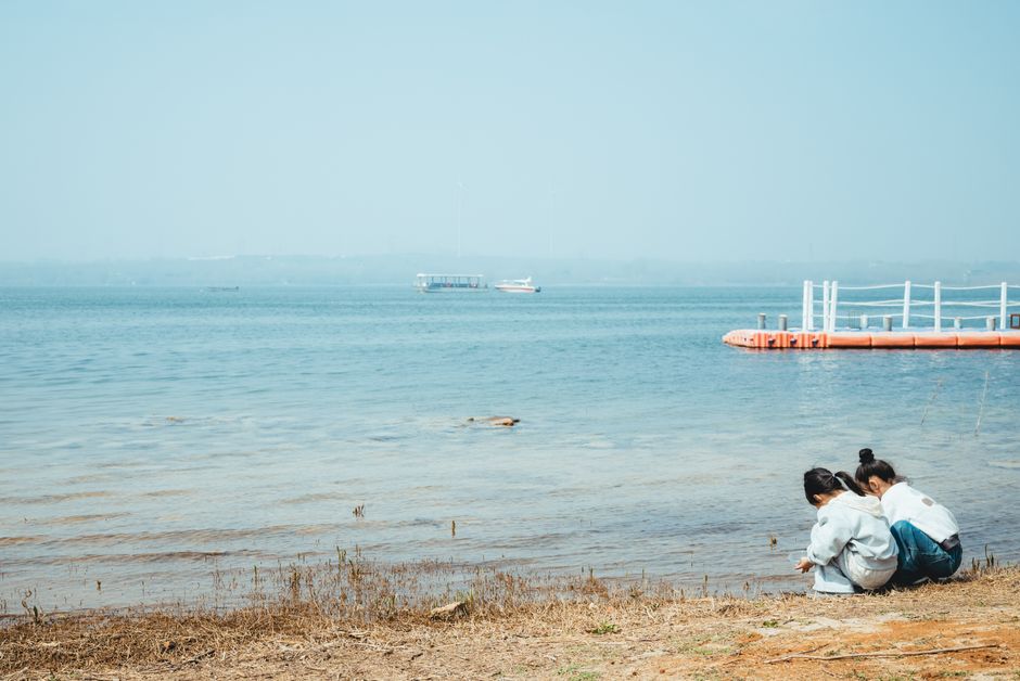Two children enjoying a calm day by the lakeside, exploring nature.