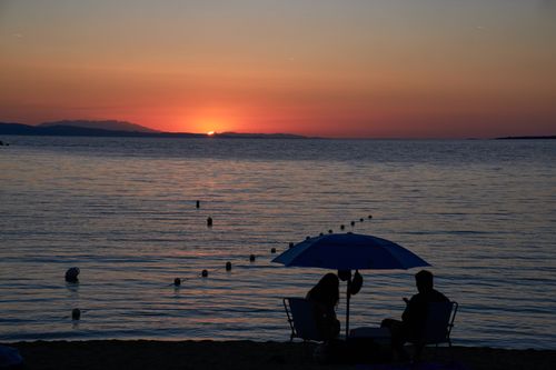 Free Romantic beach sunset scene with silhouettes by the Aegean Sea in Greece. Stock Photo