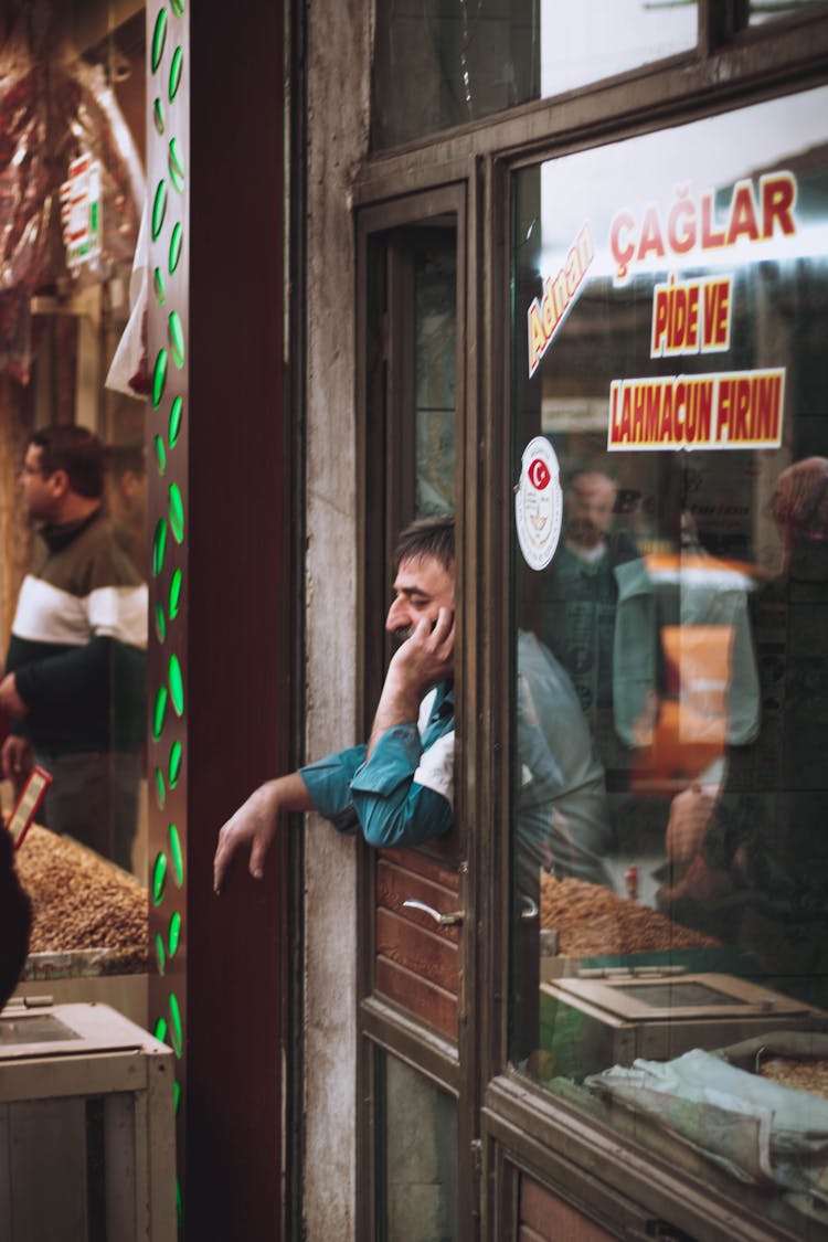 Bored Grocery Seller Bending Out Shop Window