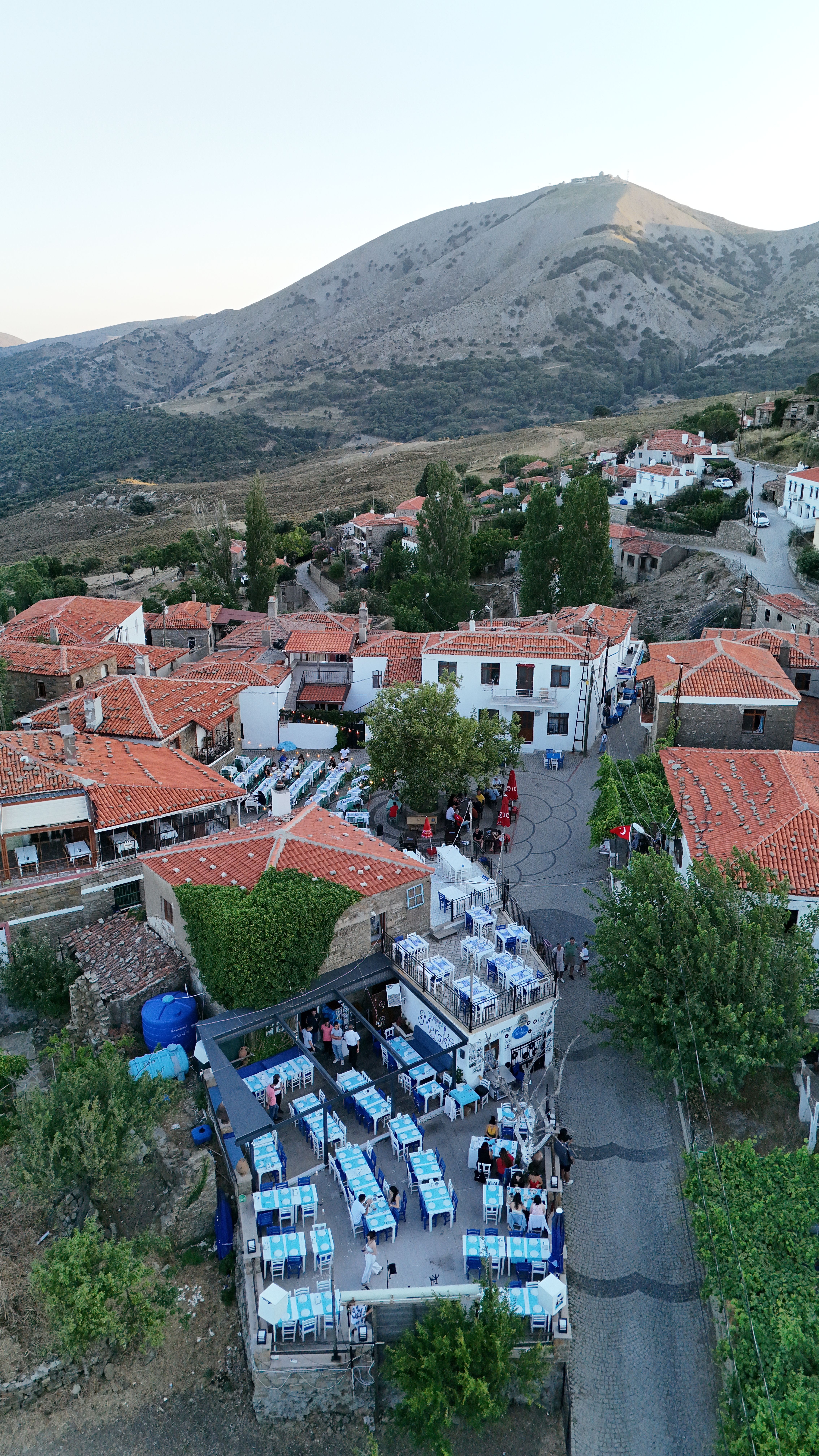 Stunning aerial shot of a traditional village in Gökçeada, Türkiye with mountain backdrop.