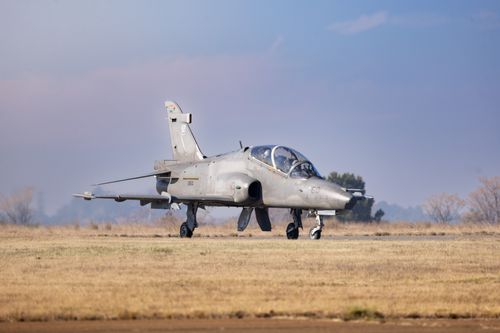 Free A military jet is parked on a runway in an open field under a clear sky, showcasing aviation technology. Stock Photo