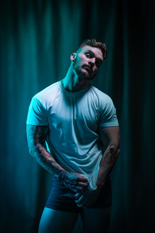 Free Edgy portrait of a muscular man with tattoos in dramatic blue lighting. Stock Photo