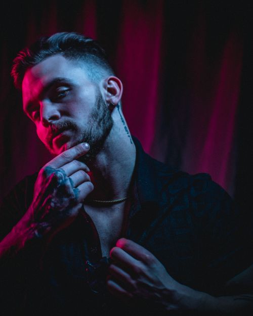 Free Dramatic portrait of a tattooed man under red and blue neon lights, evoking a moody atmosphere. Stock Photo