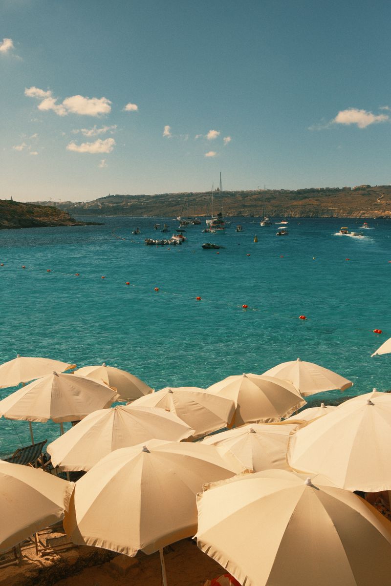 Beach umbrellas overlooking the azure waters of the Mediterranean Sea from Gozo Island, Malta.
