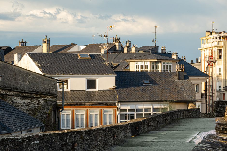 Vista de tejados tradicionales europeos con chimeneas y antenas en la cálida luz de la tarde.