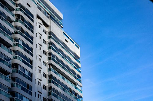 Free A modern high-rise building with glass balconies under a clear blue sky. Stock Photo
