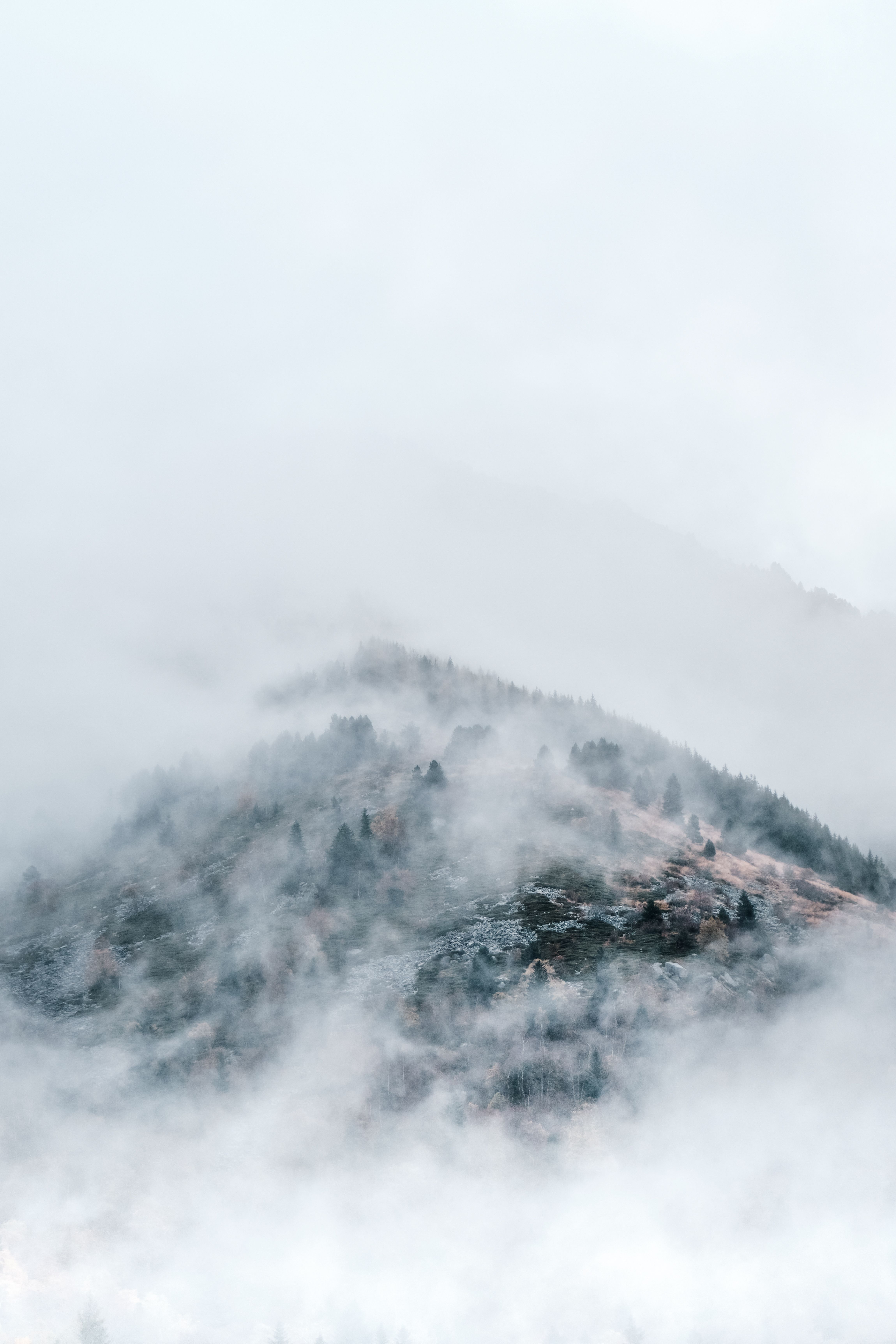 Serene misty landscape of Pyrenees mountains shrouded in fog and clouds, evoking tranquility.