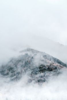 Serene misty landscape of Pyrenees mountains shrouded in fog and clouds, evoking tranquility.