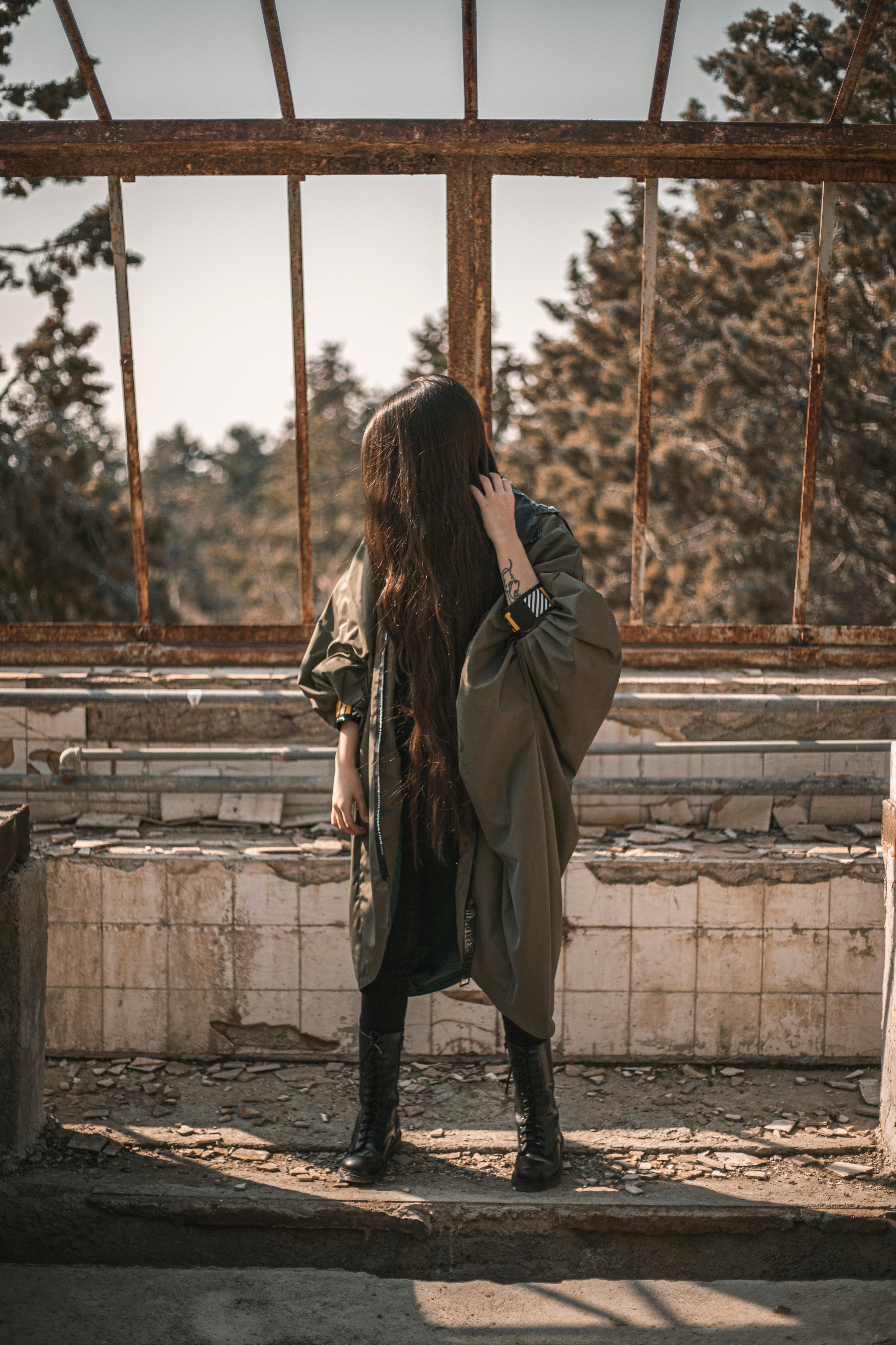 unrecognizable trendy lady standing in destroyed industrial district