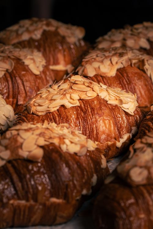 Free Close-up of freshly baked almond croissants, showcasing golden flaky layers topped with sliced almonds. Stock Photo