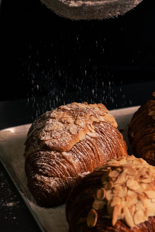 Free Delicious almond croissants topped with powdered sugar, perfect for a bakery or breakfast setting. Stock Photo