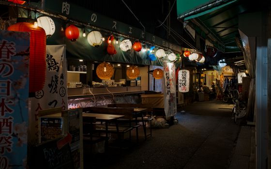 Captivating nighttime view of an izakaya adorned with lanterns in Osaka's vibrant Tenma district.