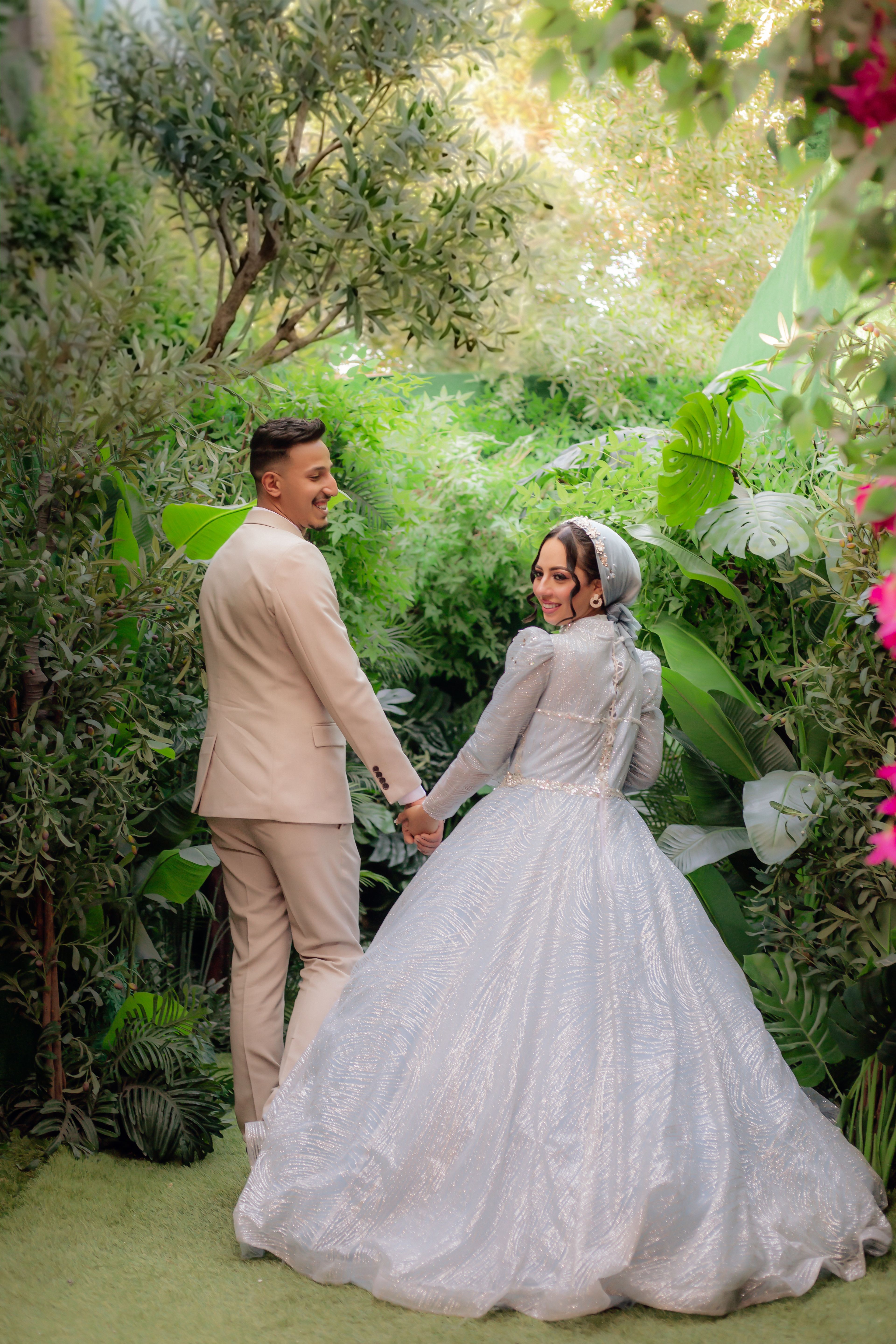 Happy couple posing in a lush green garden on their wedding day.