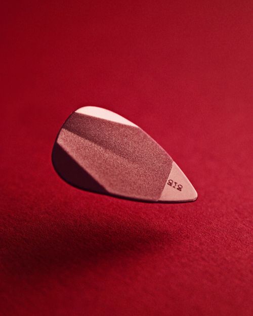Free Close-up of a guitar pick against a striking red background. Perfect for music-related themes. Stock Photo