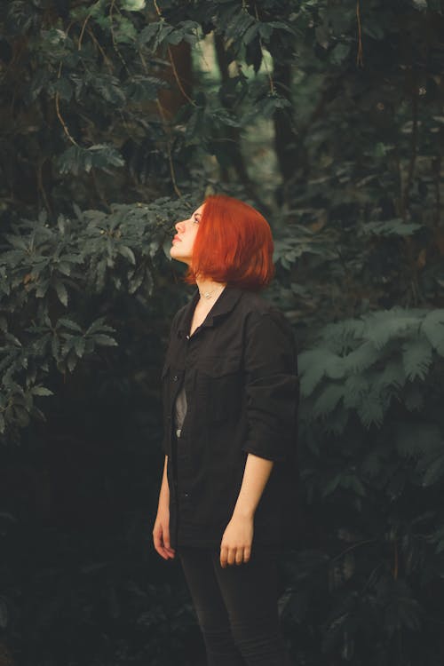 Woman in Black Button Up Shirt Standing Near Green Plants