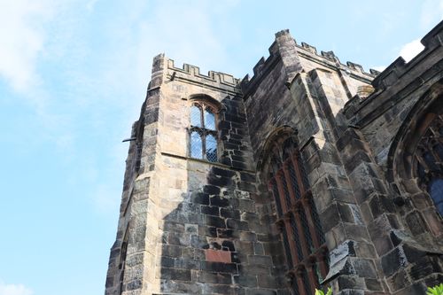 Free Close-up of a Gothic church tower showcasing detailed stonework under a blue sky in England. Stock Photo