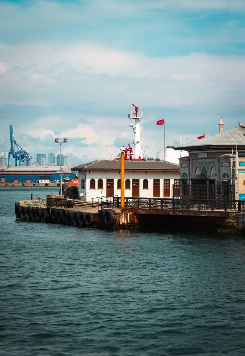 Free Vibrant image of Istanbul's harbor with ferry dock and distant skyline, capturing city's essence. Stock Photo