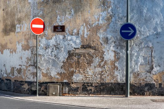 Rustic street with directional signs, highlighting urban decay and signage.