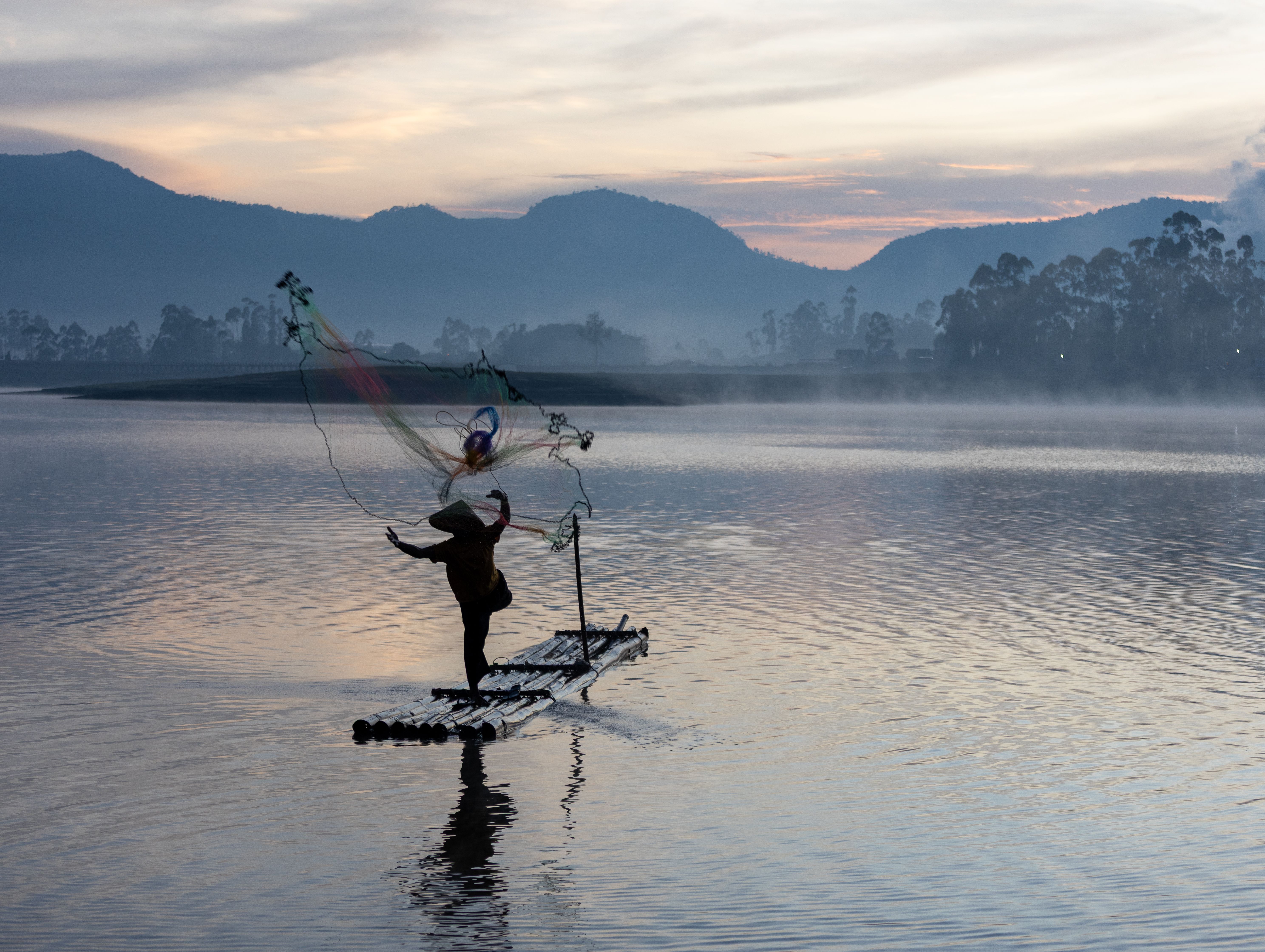 Nelayan menjala di danau berkabut