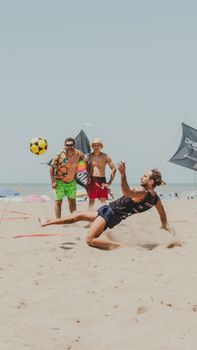Energetic beach soccer game with players at Mar del Plata, Argentina's sandy shores.