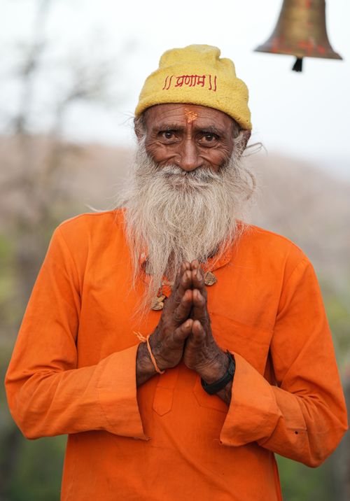Free Elderly Hindu man in orange robe performing Namaste gesture outdoors in Indore. Stock Photo