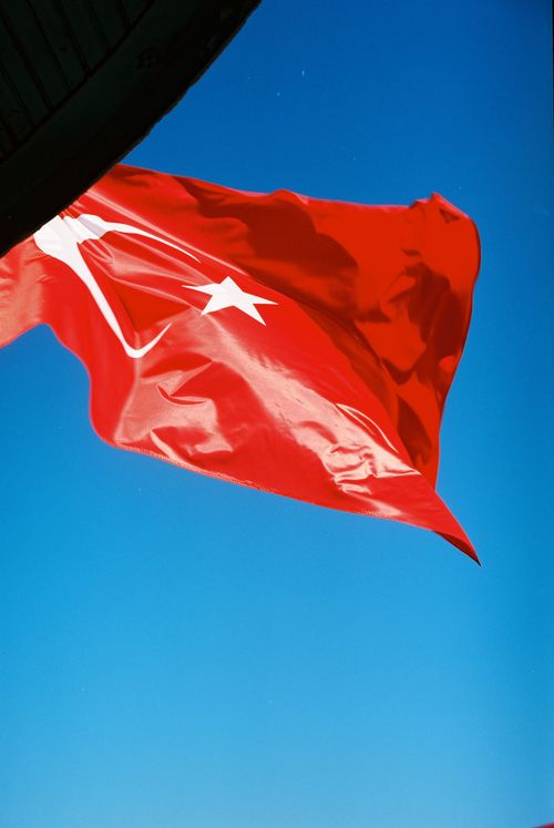 Free A vibrant Turkish flag flutters against a clear blue sky, capturing national pride. Stock Photo