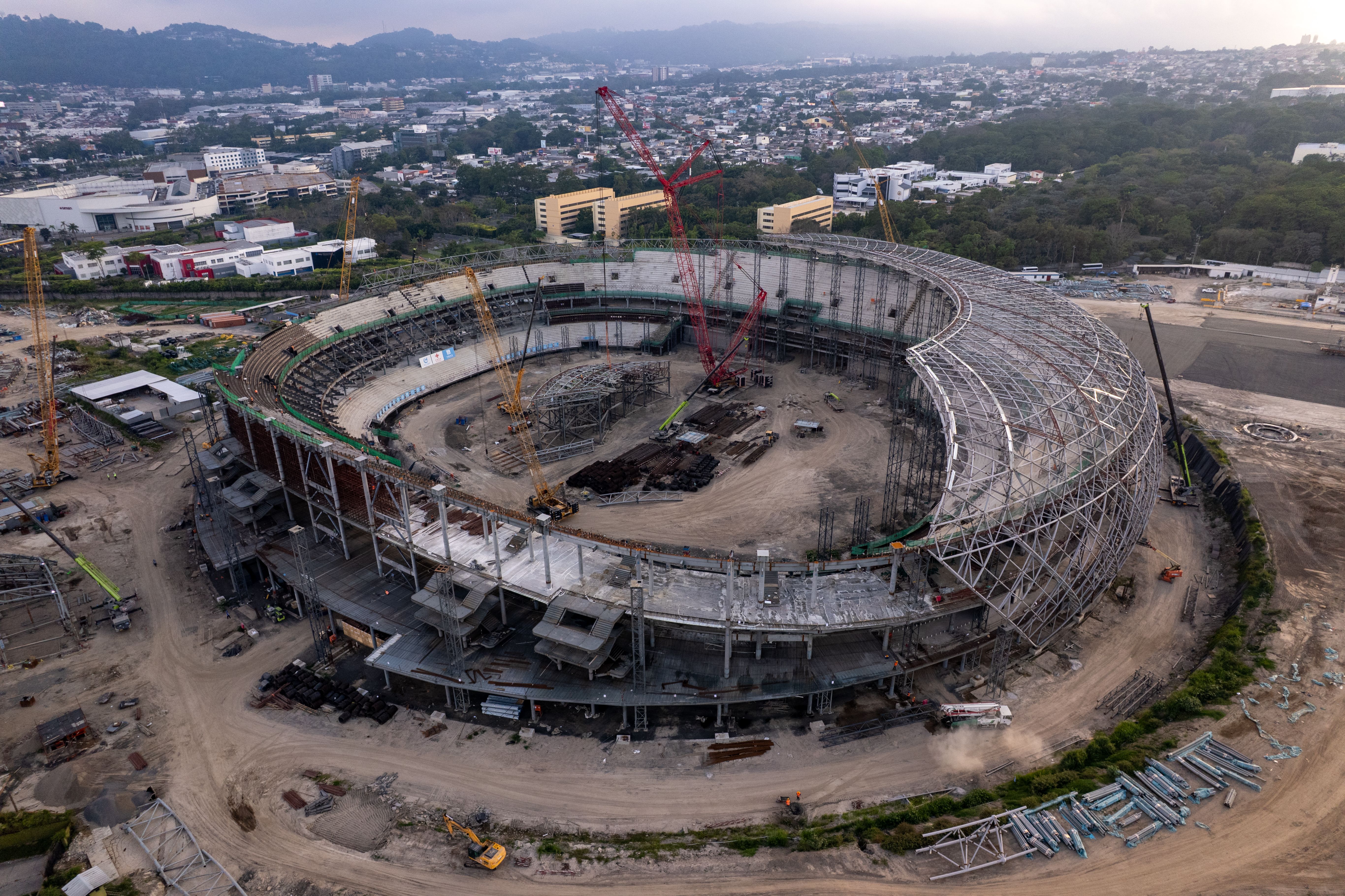 Aerial photograph of a large stadium under construction, showcasing structural progress and surroundings.