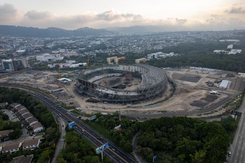 Free Aerial view of a large stadium under construction amidst a sprawling urban landscape. Stock Photo