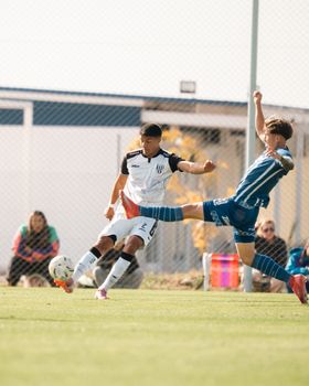 Intense soccer match with players competing for the ball on a sunlit field.