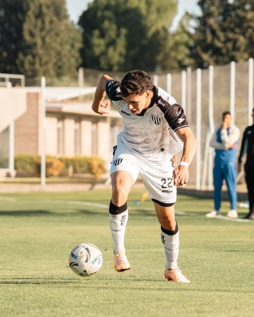 Free Focused soccer player dribbles the ball on a sunny field during a competitive match. Stock Photo