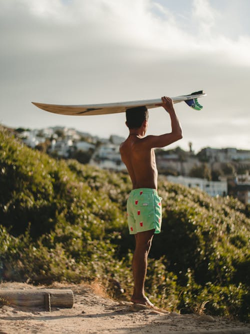 Topless Man in Green Shorts Holding Surfboard