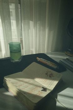 Sunlight streams onto an open notebook with a green drink beside it, creating a peaceful work atmosphere.