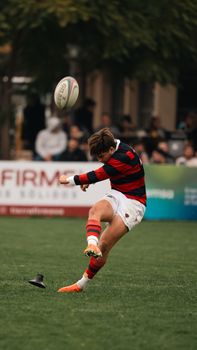 Dynamic action shot of an athlete kicking a rugby ball during a match.