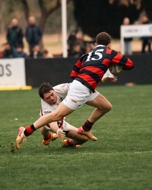 Free Dynamic rugby match moment with a player tackling another on the grass field outdoors. Stock Photo