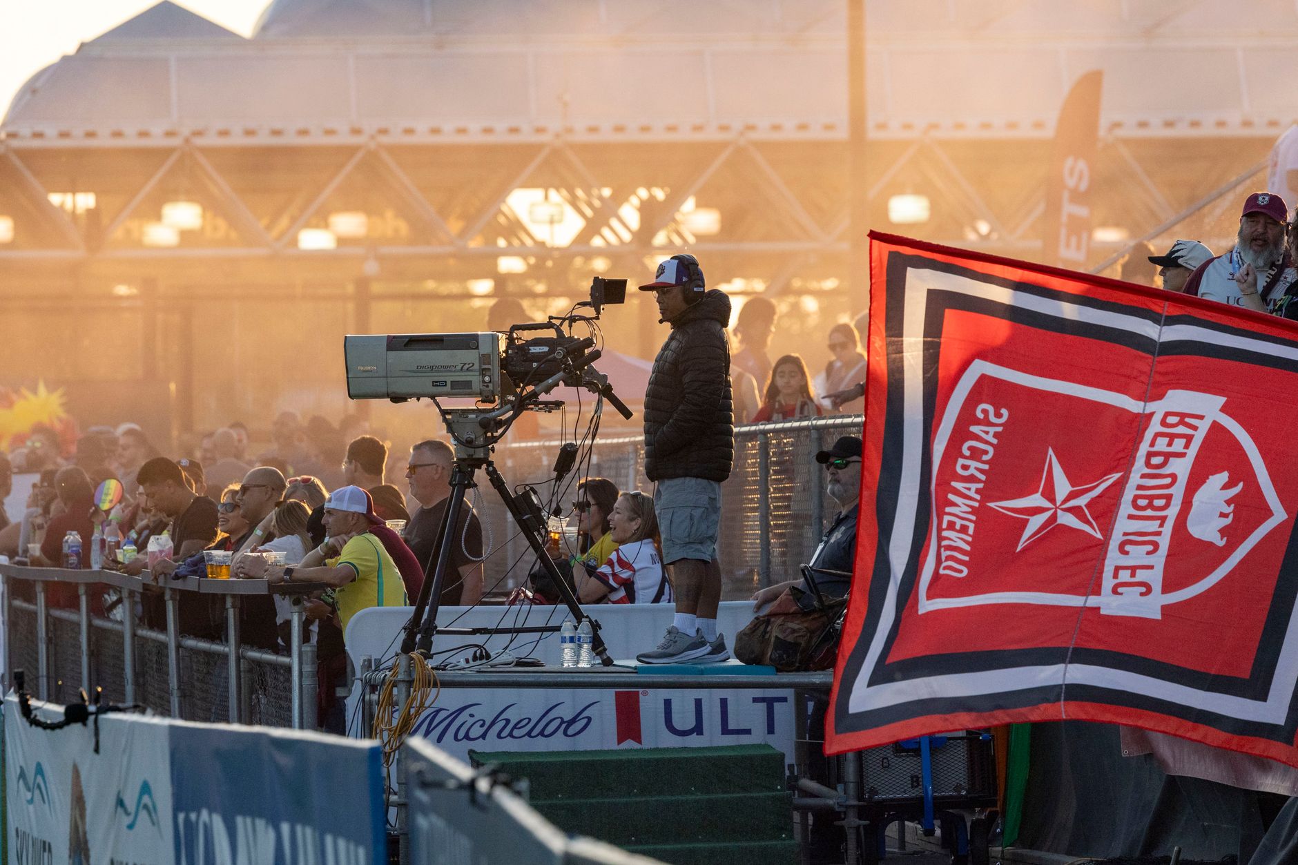 Vibrant scene of spectators enjoying an outdoor sports event at sunset.