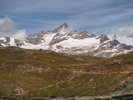 A stunning view of snow-capped mountains in Zermatt, Valais, Switzerland under a clear blue sky.